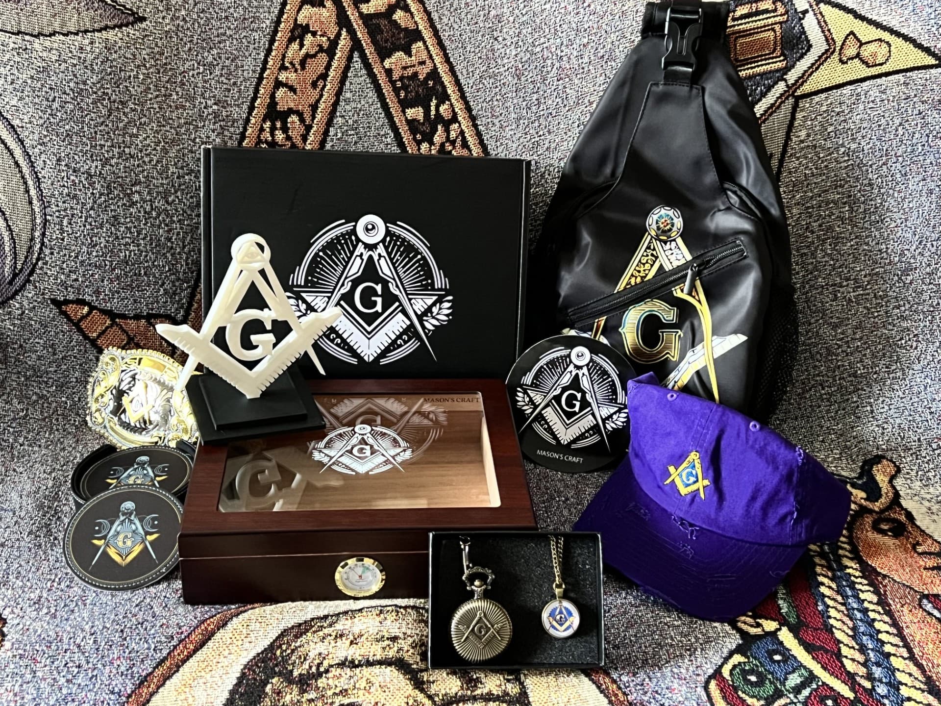 The Basket of Light — sling bag, belt buckle, pocket watch, cap, paperweight, and patch styled on a Masonic tapestry.